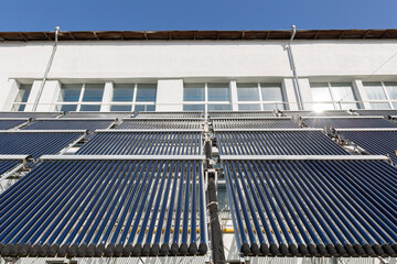 A close-up view of an evacuated tube solar water heater collector. This innovative system, angled towards the sun, represents clean energy, sustainability, and energy-saving technology. © Sodel Vladyslav