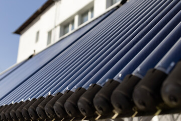 A close-up view of an evacuated tube solar water heater collector. This innovative system, angled towards the sun, represents clean energy, sustainability, and energy-saving technology.