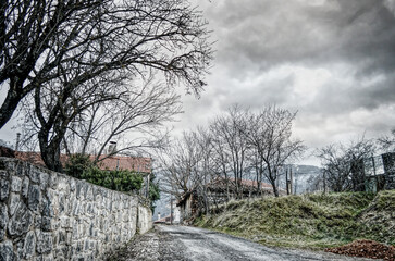 Moody winter mountain village street under dramatic cloudy sky in Greece.