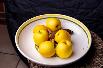 Gros plan sur un saladier contenant des pommes, une banane et un citron, mettant en valeur les textures et les couleurs naturelles des fruits frais.