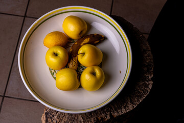 Gros plan sur un saladier contenant des pommes, une banane et un citron, mettant en valeur les textures et les couleurs naturelles des fruits frais.
