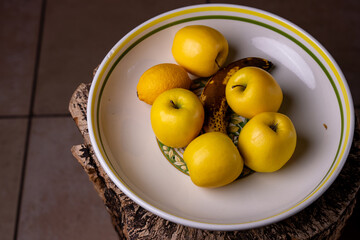 Gros plan sur un saladier contenant des pommes, une banane et un citron, mettant en valeur les textures et les couleurs naturelles des fruits frais.