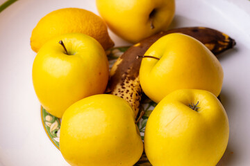 Gros plan sur un saladier contenant des pommes, une banane et un citron, mettant en valeur les textures et les couleurs naturelles des fruits frais.