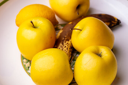 Gros plan sur un saladier contenant des pommes, une banane et un citron, mettant en valeur les textures et les couleurs naturelles des fruits frais.