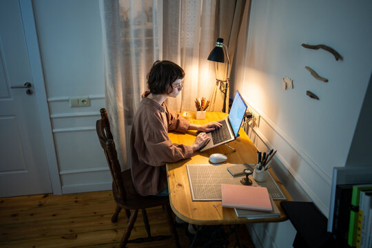 Concentrated woman working intensely on laptop during late hours, absorbed in online tasks and typing. Home office telecommuting, tense young worker, late night deadline, student electronic learning - Powered by Adobe