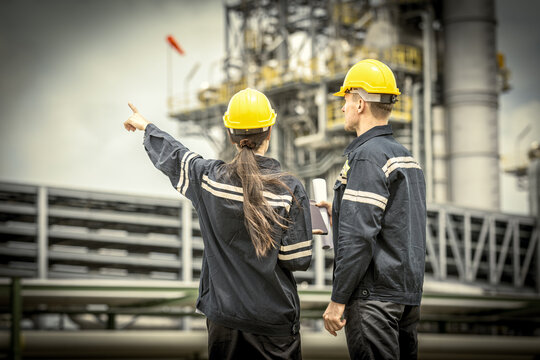 Industrial engineers workers in a refinery - oil and gas processing equipment machinery for transportation, engineers collaborate with a laptop, blueprint, and digital tablet at the oil storage tanks