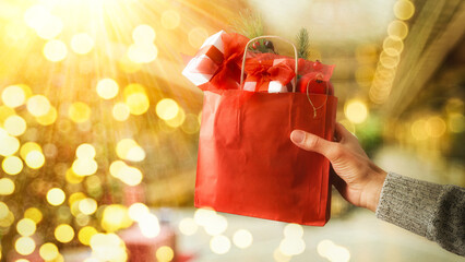 Hand holding shopping bag full of gifts outside sunny
