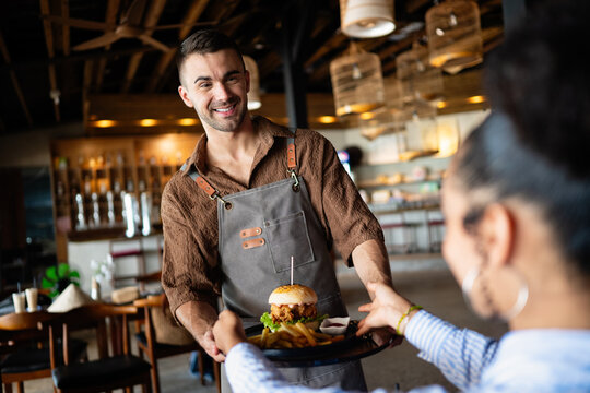Casual dining lifestyle, waiter serves a delicious burger and fries in a relaxed restaurant setting - Powered by Adobe