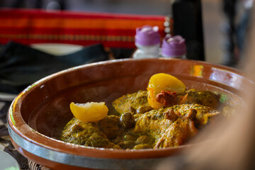 Chicken tagine, traditional Moroccan dish of chicken pieces braised with spices, olives, and preserved lemons.. Traditional Moroccan chicken tagine with olives and salted lemons, selective focus. 