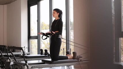 Woman trainer exercising on pilates reformer - Powered by Adobe