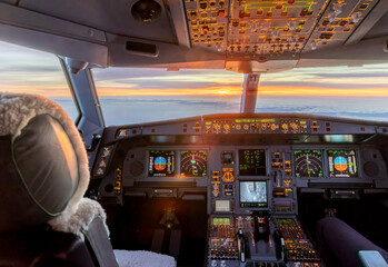 Illuminated airplane cockpit at sunrise during commercial flight