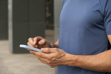 Man using and texting mobile phone. Check apps, focused on device, chatting or browsing internet. Online. Outdoors.