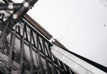 Parking gate spring broken on overhead sectional door. Garage door torsion spring is torn apart close to the ceiling, inside. Emergency clamp and replacement needed. Selective focus.