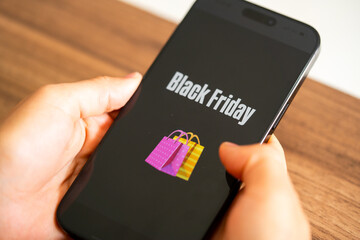 Black Friday photo. Minimalist Black Friday symbol with cell phone in hands and discount offer. Horizontal design for Black Friday sales, advertising, and social media.