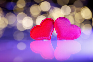Fototapeta premium Two red hearts with golden bokeh lights. Romantic holiday background for Valentine’s Day, anniversary, wedding, or New Year greeting cards. Symbol of love, joy, and celebration.