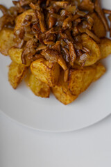 Delicious oven baked potatoes with chanterelle mushrooms served on a white plate. Top down food shot for recipe blogs, cooking magazines, or restaurant menus. Rustic comfort food at its best.