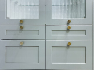 Symmetrical mint cabinetry with multiple brass knobs and fluted glass panels, balanced design, framed shaker doors, serene pastel palette delivering timeless interior storage aesthetic