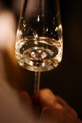 Hand with a glass of wine in the night atmosphere of the restaurant