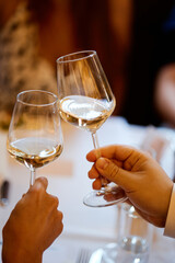 Hand with a glass of wine in the night atmosphere of the restaurant