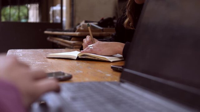 Young woman takes handwritten notes in outdoor coworking space