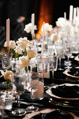 Luxurious setting of dark restaurant tables with candles and fresh flowers