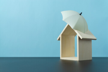 Umbrella toy and mini wooden home show the insurance cover concept
