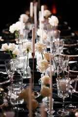 Luxurious setting of dark restaurant tables with candles and fresh flowers
