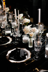 Luxurious setting of dark restaurant tables with candles and fresh flowers