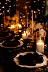 Luxurious setting of dark restaurant tables with candles and fresh flowers