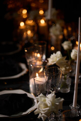 Luxurious setting of dark restaurant tables with candles and fresh flowers