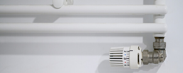 Thermostatic radiator valve installed on heating radiator edge with temperature control dial.