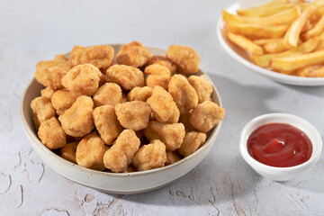 Crispy chicken popcorn with ketchup and French fries on a white background. Fast food.