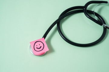 A stethoscope on light green background with a smile emoji