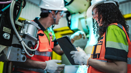 Two robotics engineers in an R and D lab perform diagnostics on an artificial intelligence robot. They are inspecting the complex hardware and system data on a tablet.