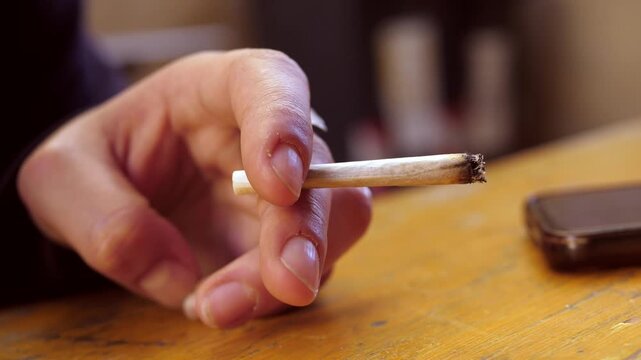 Close-up of cigarette burning between female fingertips
