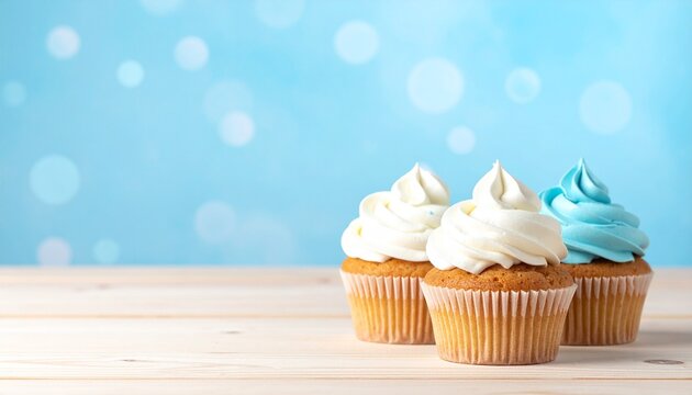 Three delicious vanilla cupcakes with blue and white buttercream frosting on a wooden table against a bright blue bokeh background, with copy space
