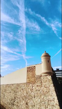 Muralla del baluarte de Badajoz con cielo azulado y nubes de aviones