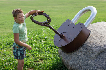 A little boy playing in the park and trying to unlock a huge lock