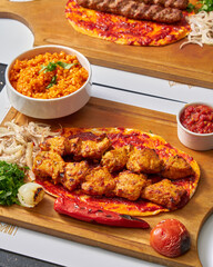 Close up of turkish kebab and chicken kebab on flatbread with rice and tomato sauce on wooden board
