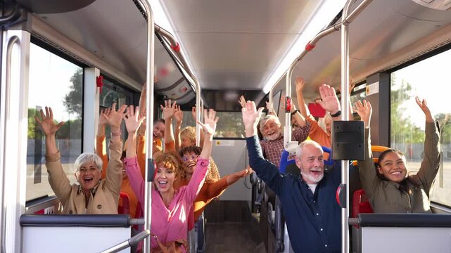 Multi ethnic group of passengers sitting on a public city bus. Happy people of different ages having fun, waving their hands, and cheering