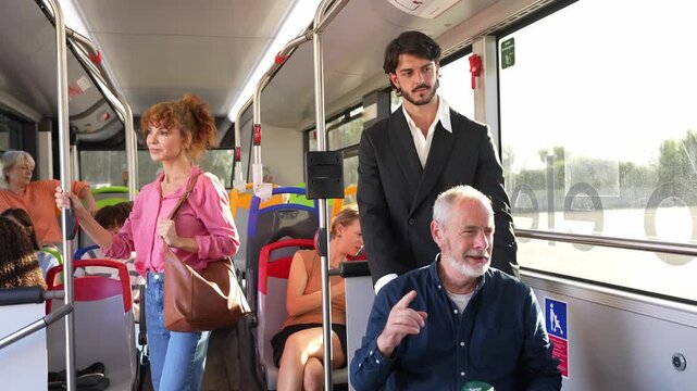 Diverse group of people commuting on a public bus. An elegant man helps an older gentleman in a wheelchair while other passengers sit or stand