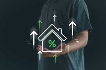 Person holding a digital house icon with percentage and upward arrows, symbolizing increasing mortgage interest rates, property investment, and real estate market growth.