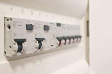 Row of circuit breakers inside modern electrical panel, selective focus view. Industrial energy distribution system and safety technology concept.