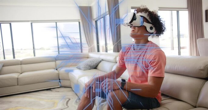 Man wearing VR headset at home raising hand, activating blue grid and code, exploring tech demo