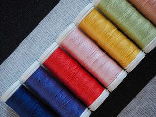 Multicolored spools of thread on black and white striped textile background