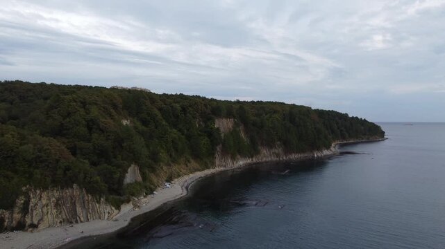 Drone footage flying diagonally from sea towards land with Kiseleva Rock cliff on left