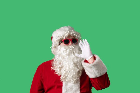 Santa Claus with a white curly beard, wearing a red suit and sunglasses, is shouting with his hands cupped around his mouth against a green background. Ideal for Christmas themed compositions. - Powered by Adobe