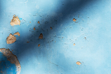 A wall painted blue with the plaster falling off