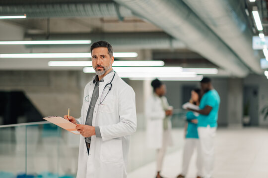 Male doctor holding clipboard and observing hospital hall - Powered by Adobe
