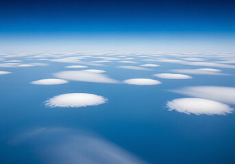 Aerial view of scattered white lenticular clouds against a clear blue sky image